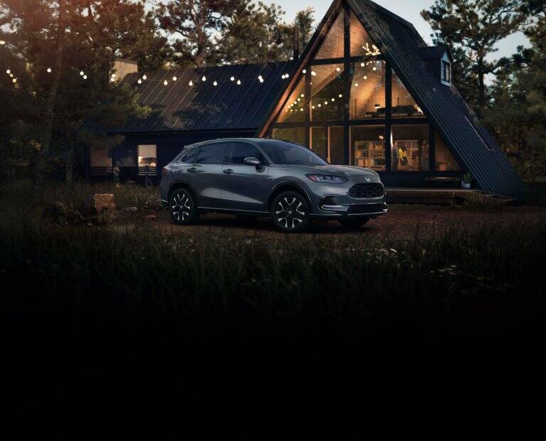 2027 Honda HR-V EX-L in Nordic Forest Pearl three quarter view parked in front of a cabin (Subcompact Crossover SUV).